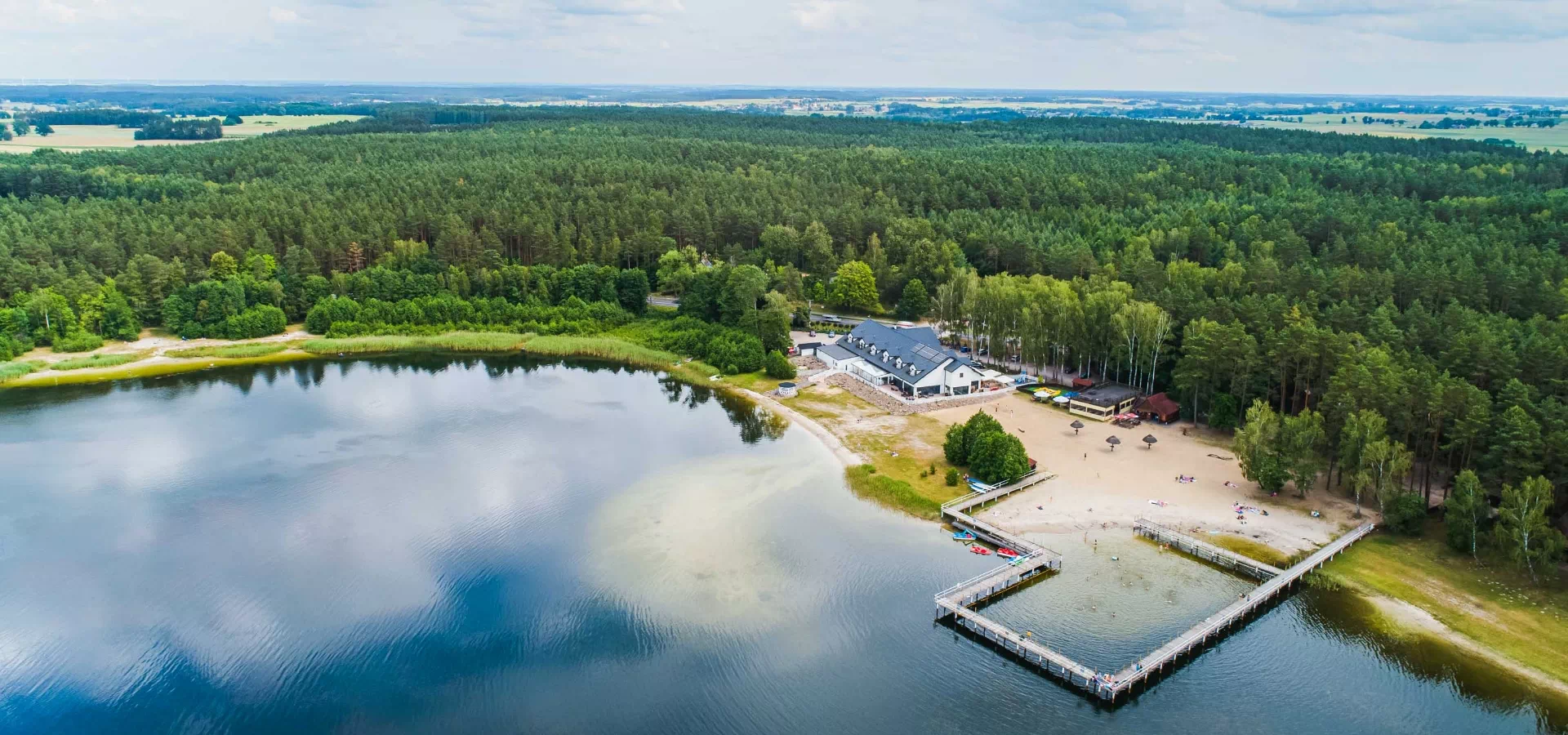 Jezioro Płaczewskie, piaszczysta plaża i ośrodek w otoczeniu lasu